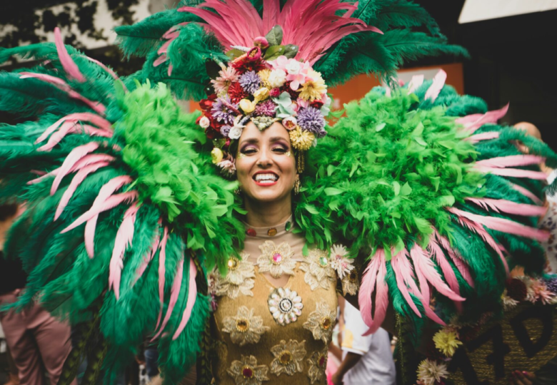 Person wearing a Vibrant Carnival Costume with colorful feathers and floral headpiece perfect for a festive celebrations.